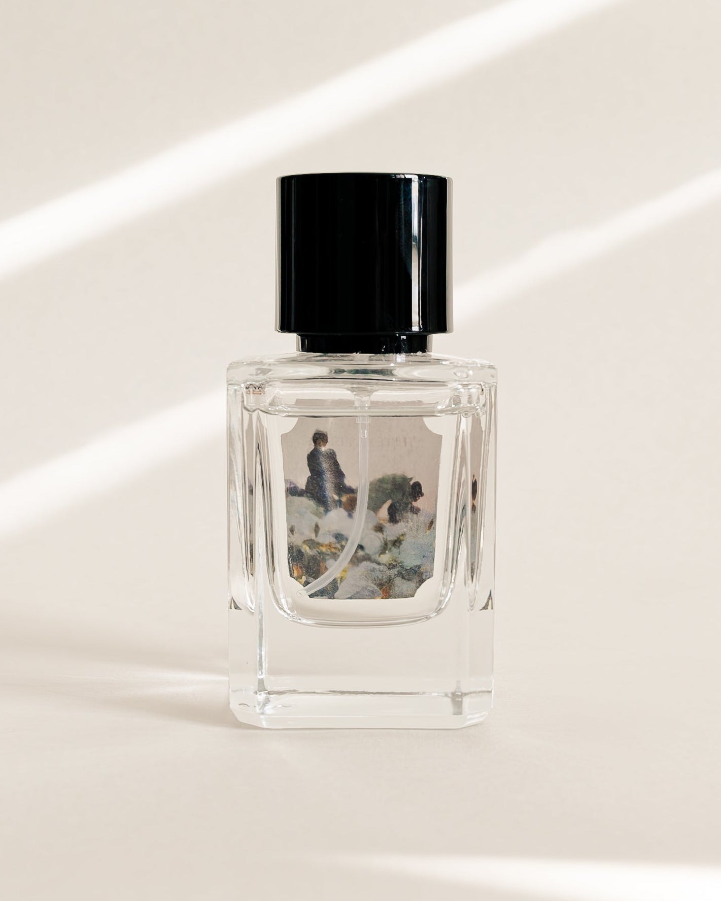 Small perfume bottle with black cap on a light surface