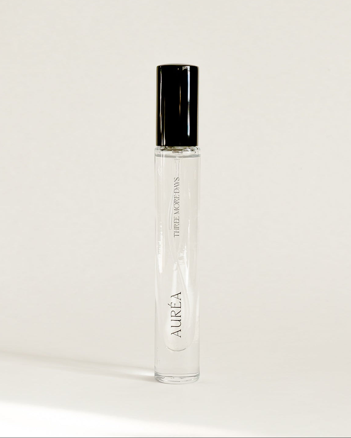 A clear glass perfume roller bottle with a black cap, standing upright on a white surface against a white backdrop. The brand name 'AUREA' is printed vertically on the bottle.