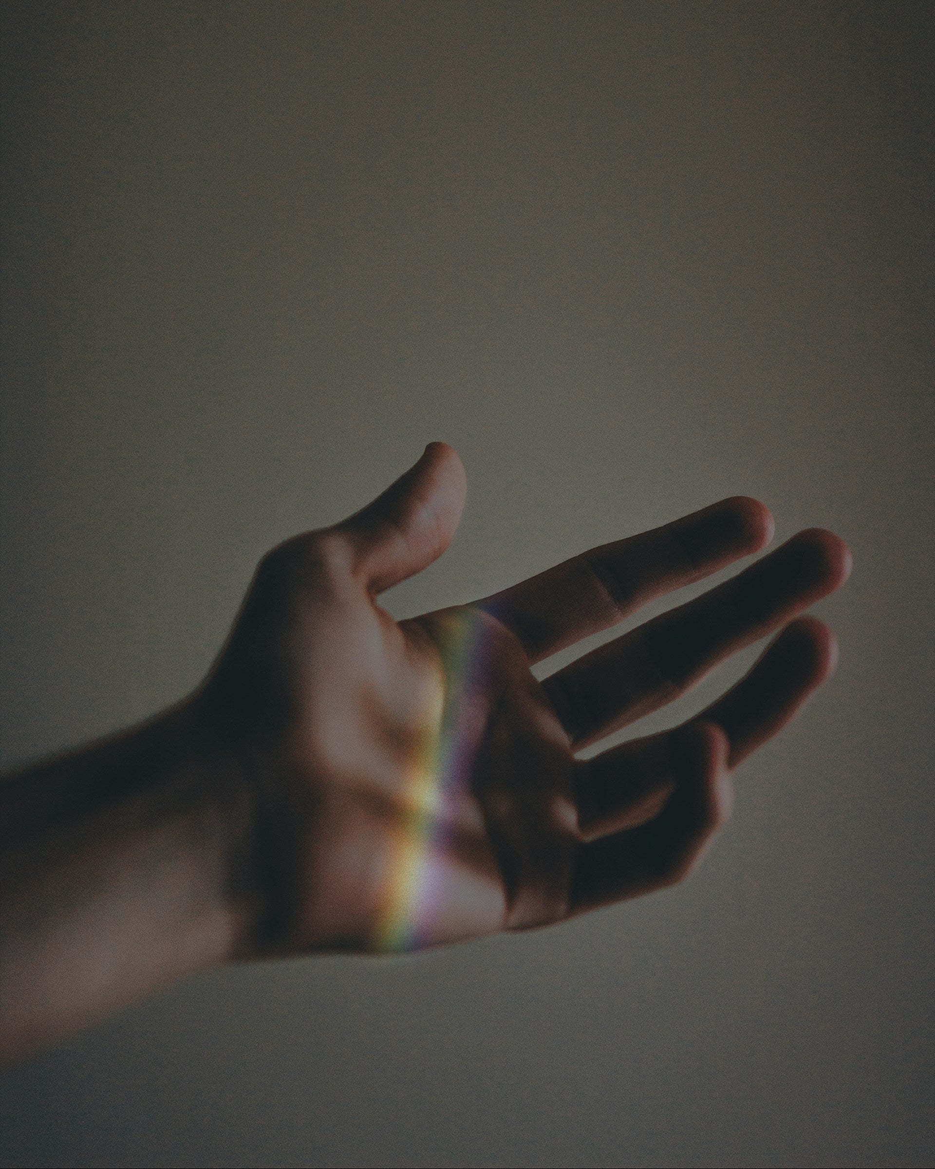 Hand with rainbow reflection on a plain background