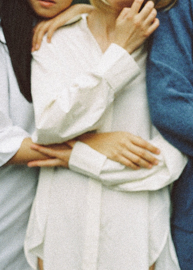 Two people embracing, one in a white outfit and the other in a blue outfit.