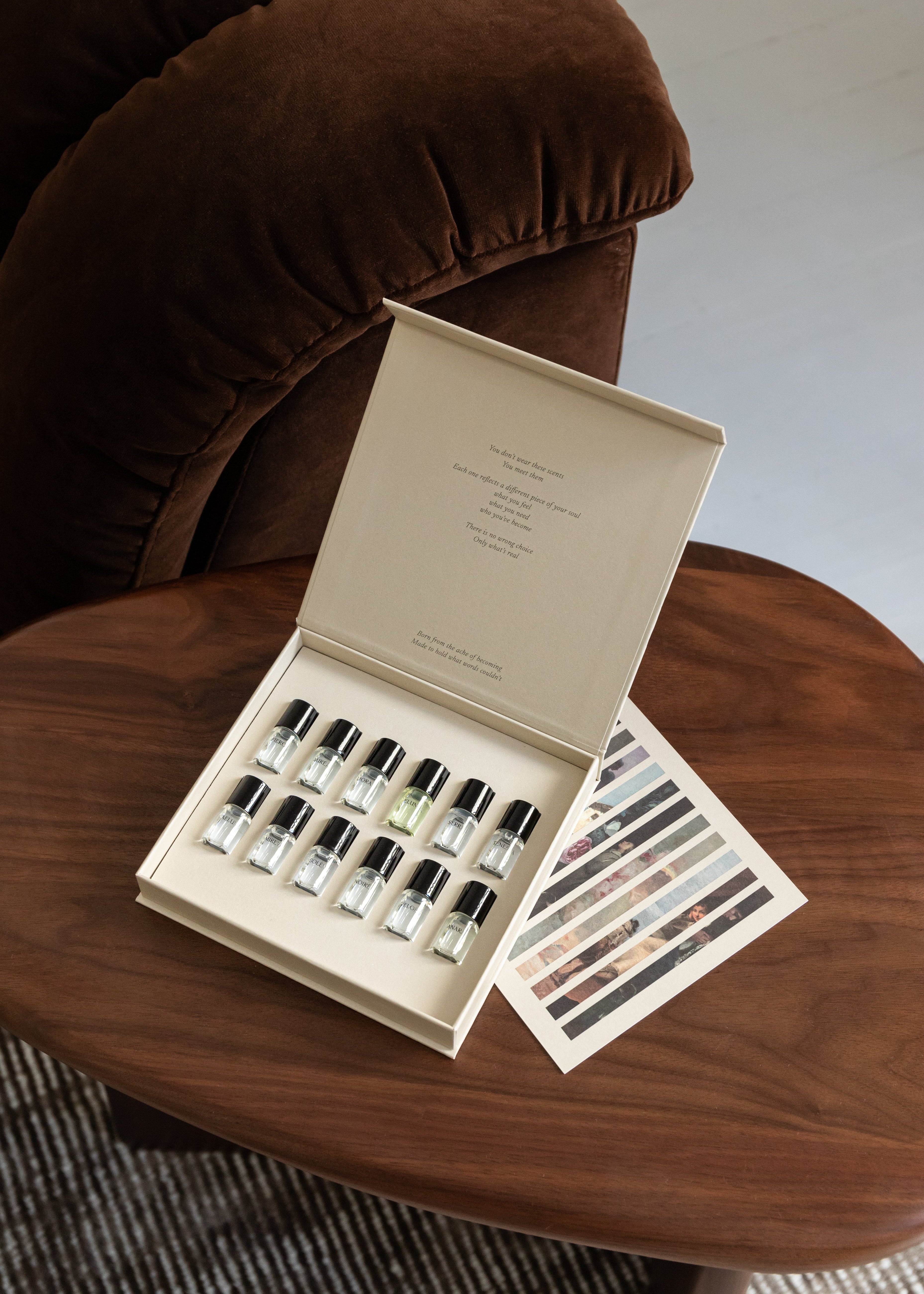 Set of small bottles and color swatches on a wooden table with a brown cushioned chair in the background.