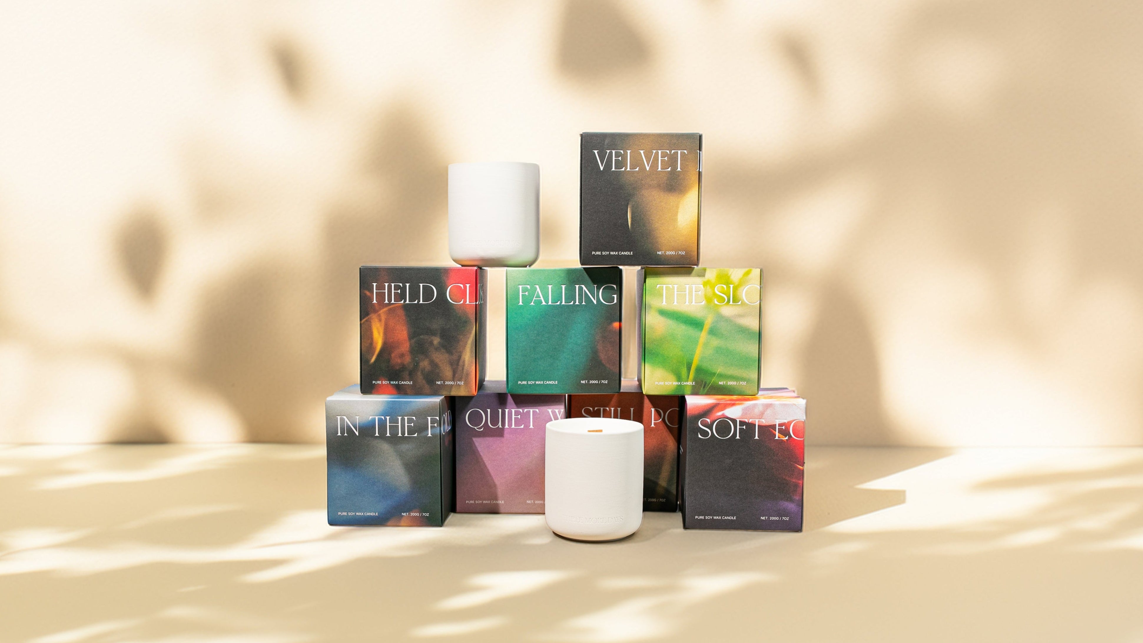 Collection of colorful boxes and candles on a beige surface with soft lighting
