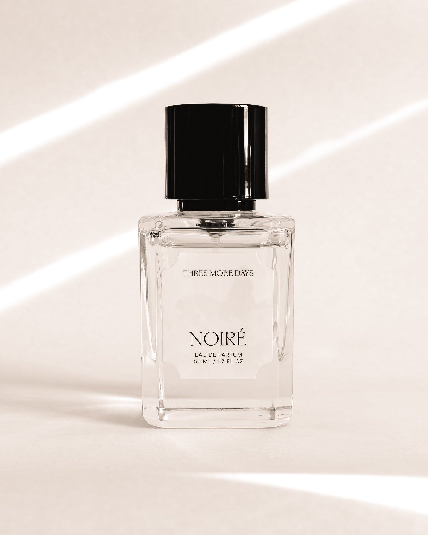 Perfume bottle labeled 'Noire' on a white surface with soft lighting