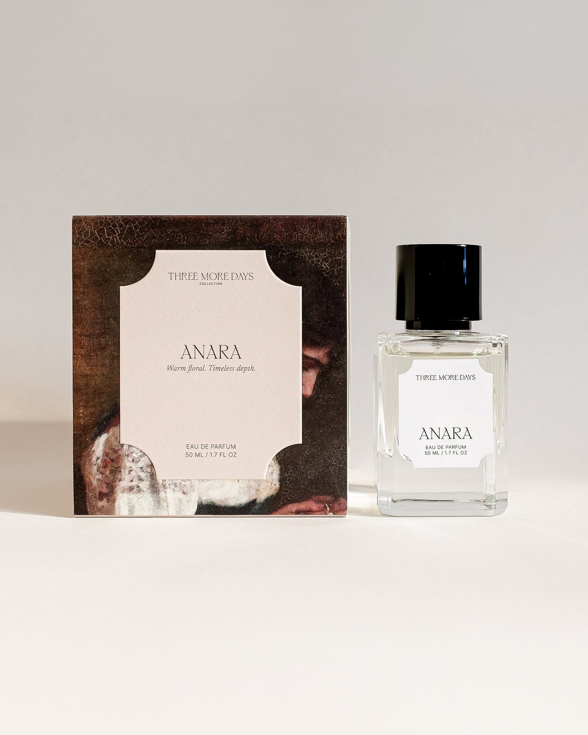 A small clear glass perfume bottle with a black cap stands next to its rectangular box packaging on a clean white surface against a light gray background. The label reads ANARA.