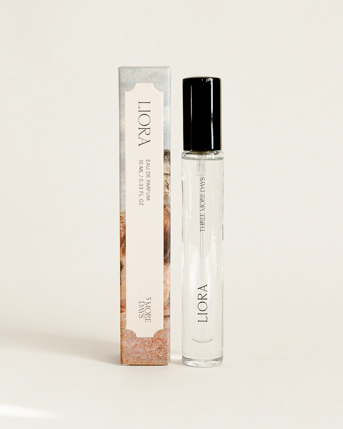 A clear glass roller bottle with a black cap stands next to its matching rectangular box on a white surface. The packaging features a soft pink and white floral design with the brand name 'LICORA' visible.