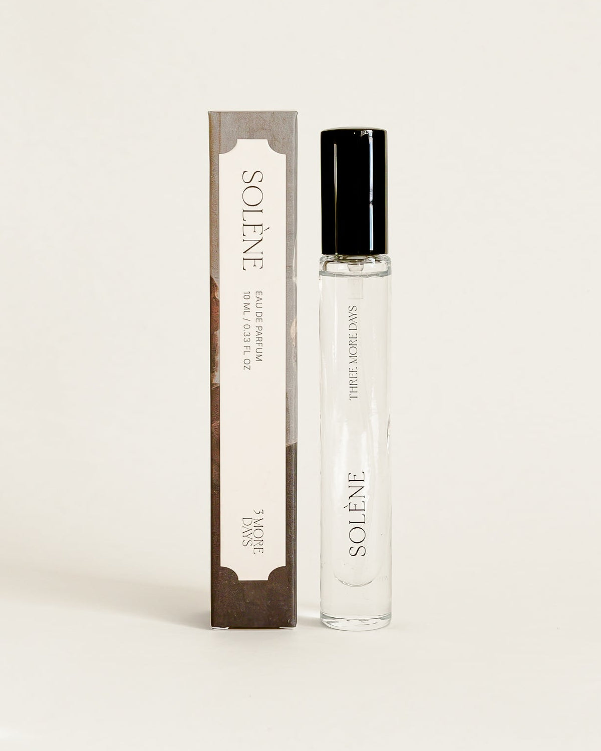 A small cylindrical cosmetic bottle with a black cap stands next to its matching rectangula