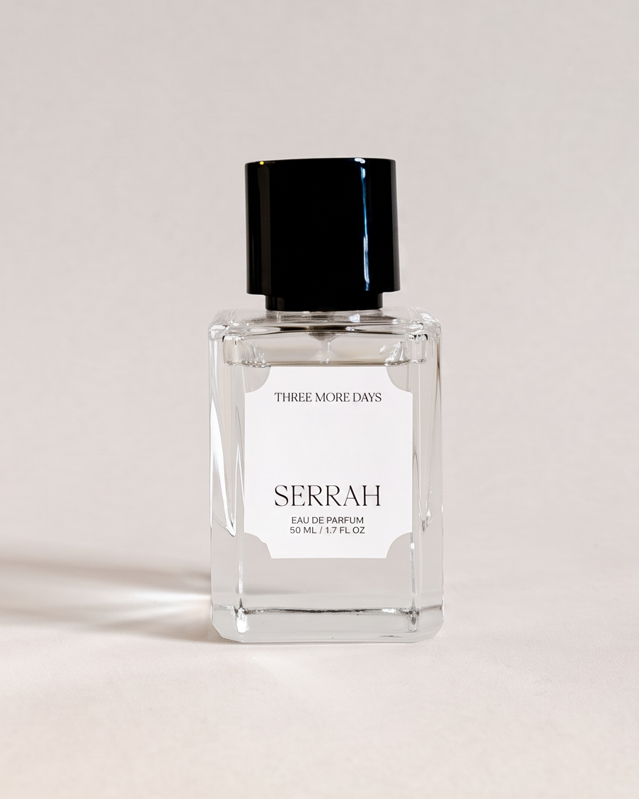 A small rectangular glass perfume bottle with a black cap and a white label reading 'SEBRAH' and 'SPOON OF THE GODS', photographed against a draped white paper backdrop.